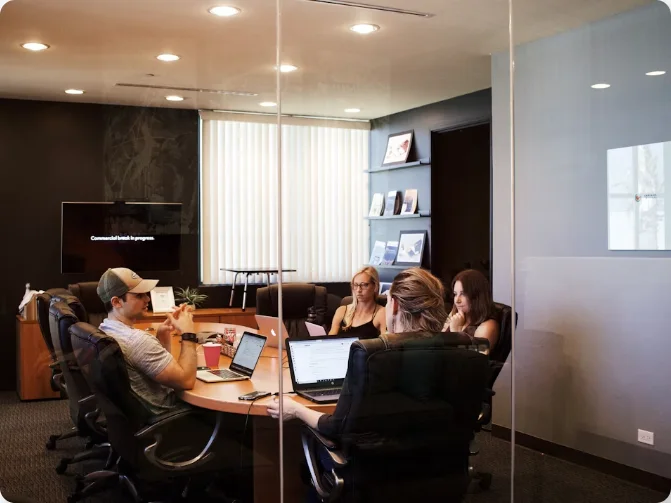 Team meeting around a conference table in a glass-walled meeting room